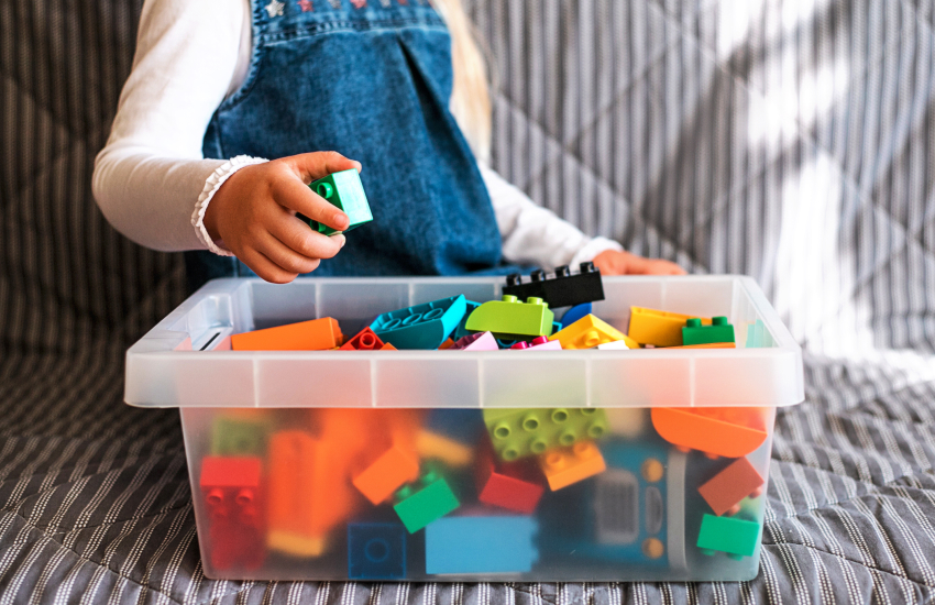 child putting toys in a box